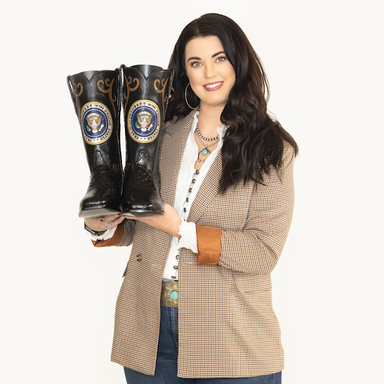 Shelbi Tidwell with brown hair holding colorful patriotic boots made for Donald Trump.